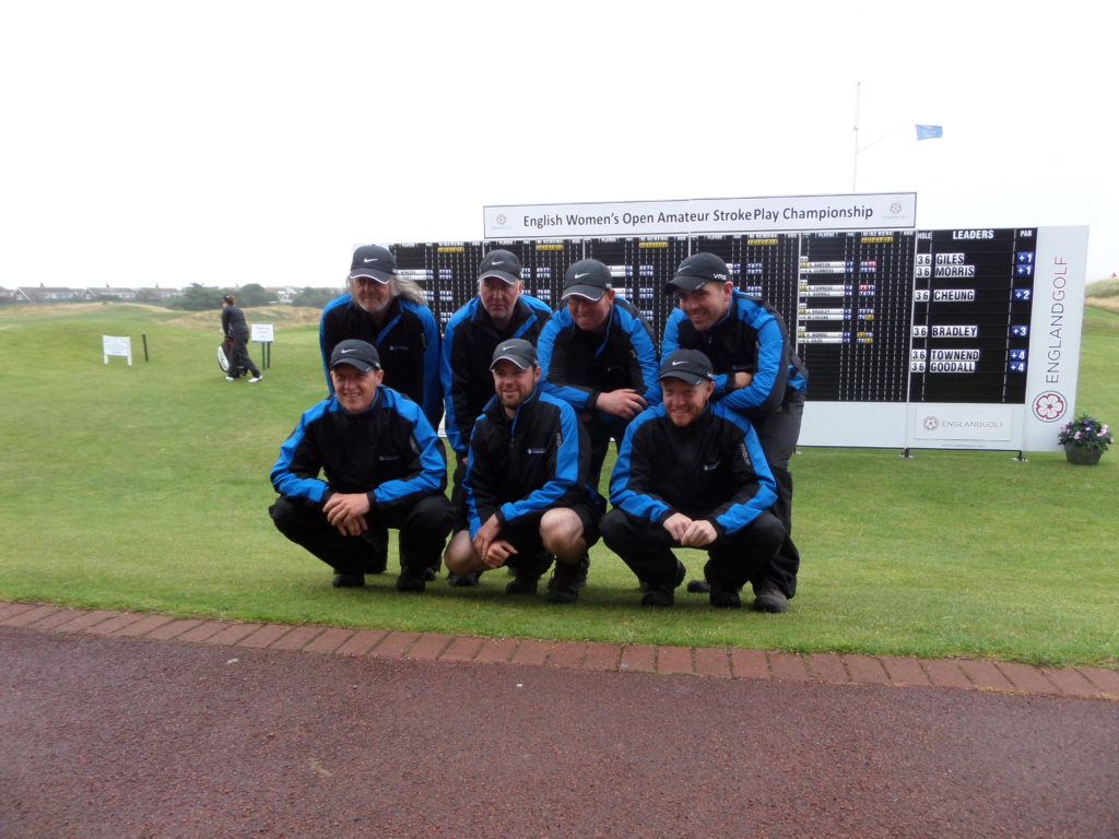 A photograph of the Greenkeepers in front of the 2015 English Women's Open Amateur Stroke Play Championship Leaderboard which shows Sammie Giles and Rochelle Morris as joint leaders after 36 holes, by kind permission of St Annes Old Links Golf Club