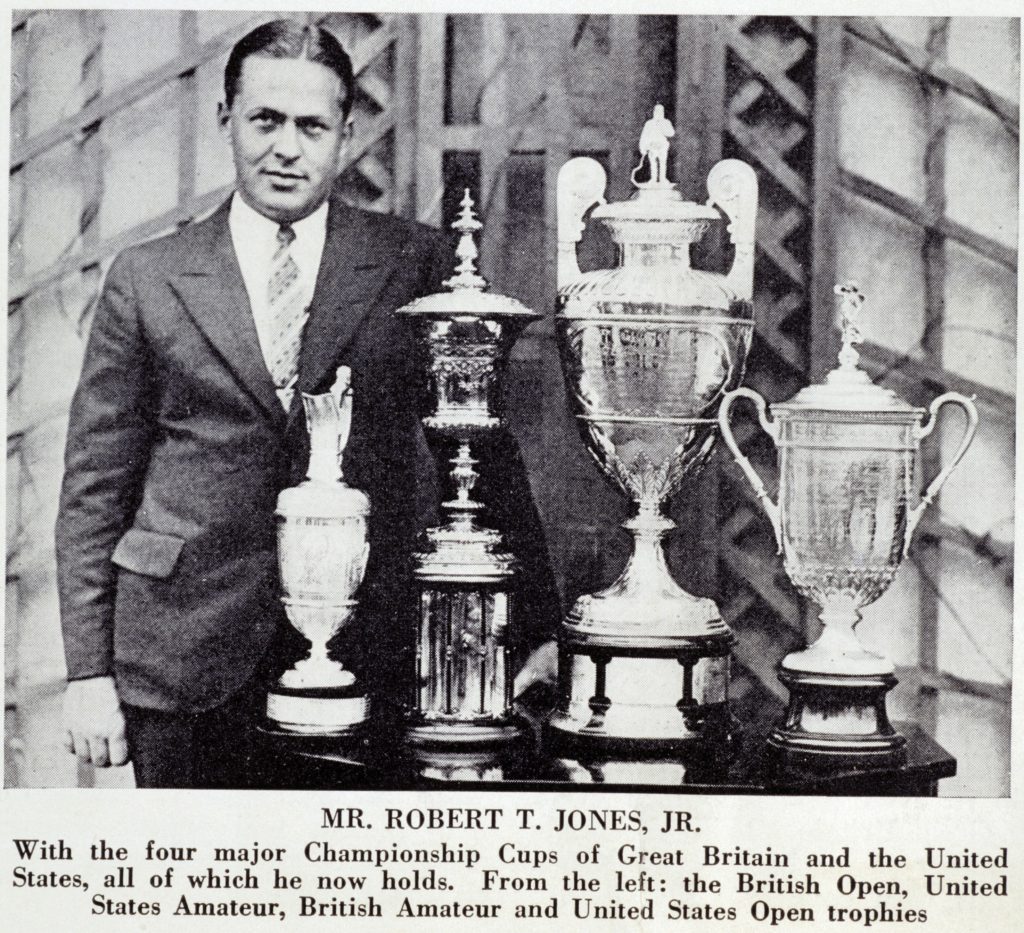 A photograph of Bobby Jones standing with the four major championship trophies from his Grand Slam in 1930