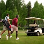 Photograph of three golfers chasing a golf buggy, driven by the other golfer in their group